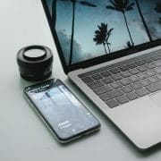 laptop and cellphone with a camera lens beside them.