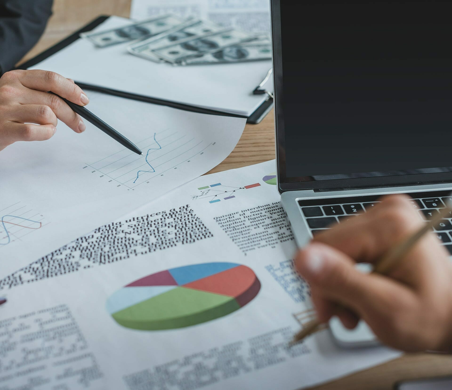 2 people at a desk going over pie charts and graphs.