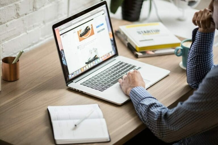 A man working on a laptop with a calendar beside him.