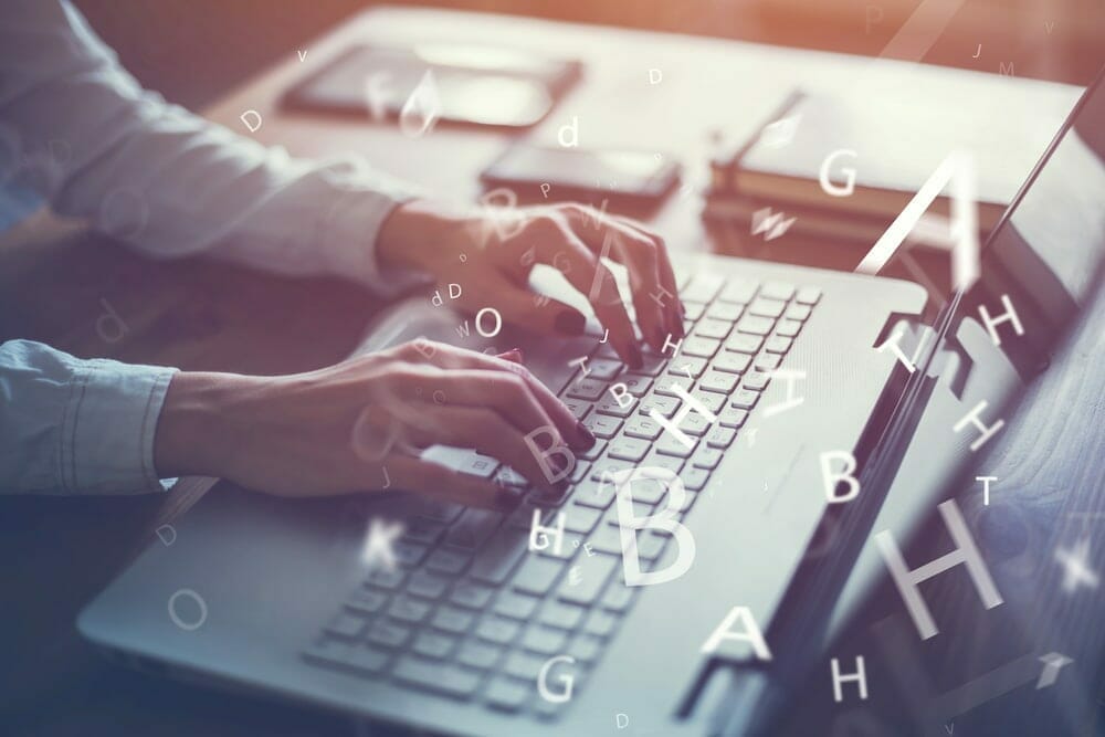 Woman typing on a laptop with the alphabet superimposed over the image at random.