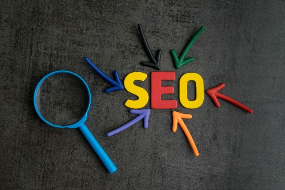 Colourful graphic with SEO letters surrounded by coloured arrows and magnifying glass