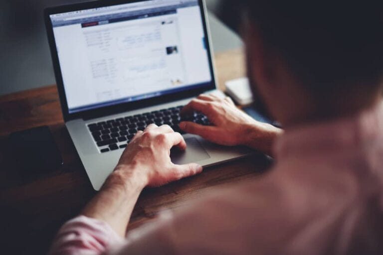 Man at a desk typing in a laptop computer