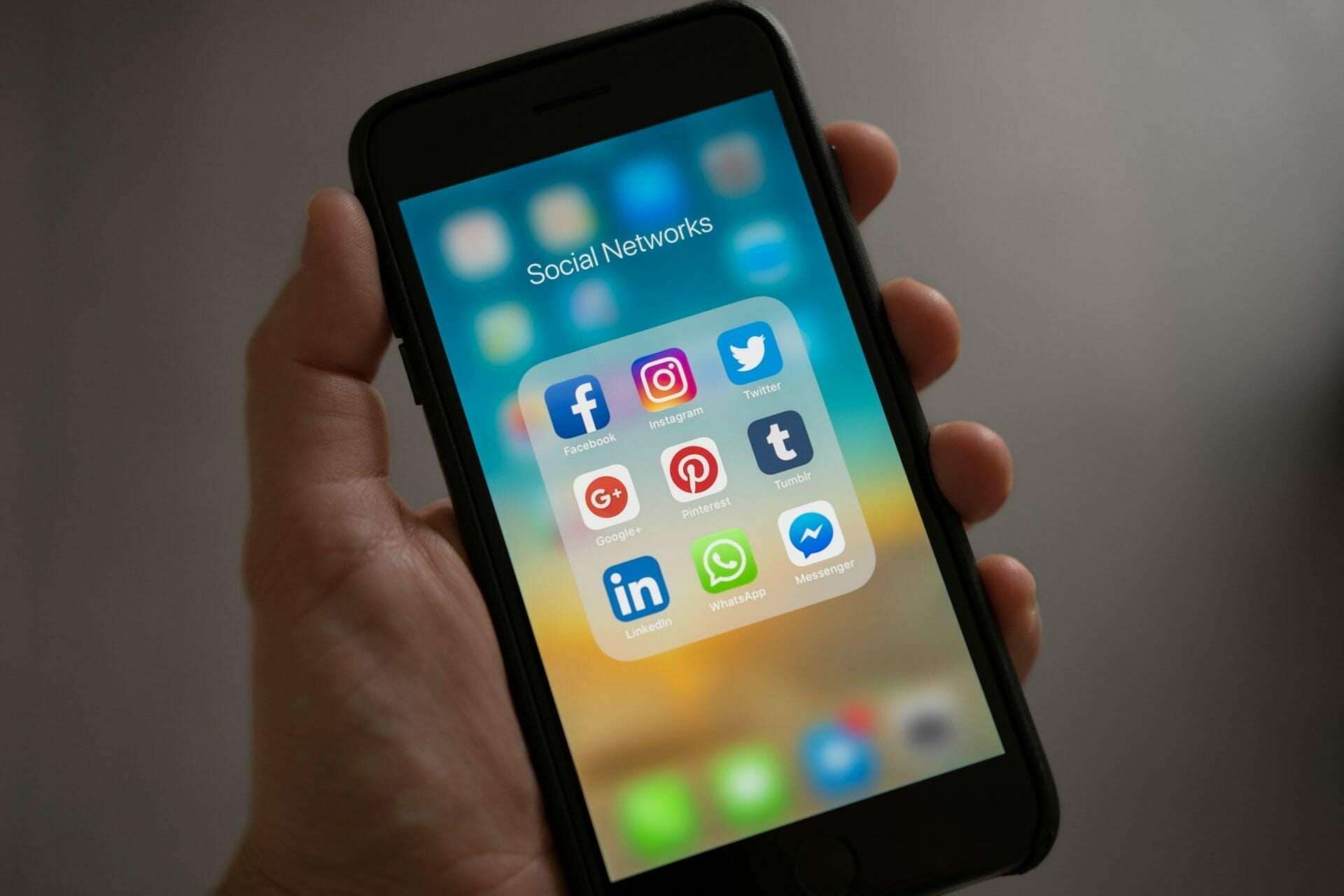 Hand holding a cell phone displaying Social Network icons