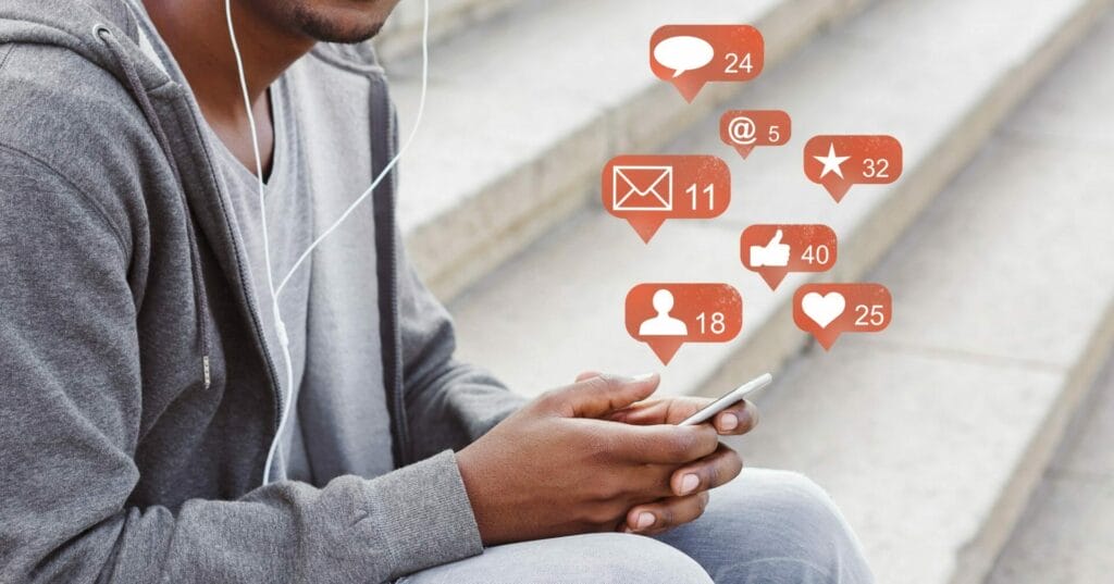 Man sitting on steps with cell phone plus a group of animate icons above showing what he has been doing on the phone