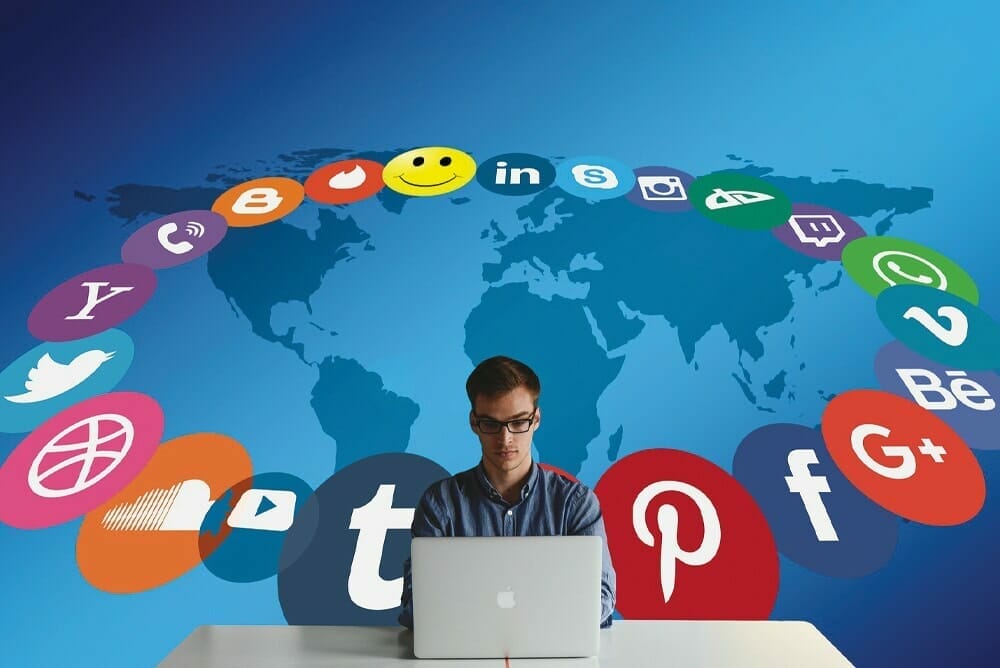 Male with a MacBook and Social Media icons swirling around him