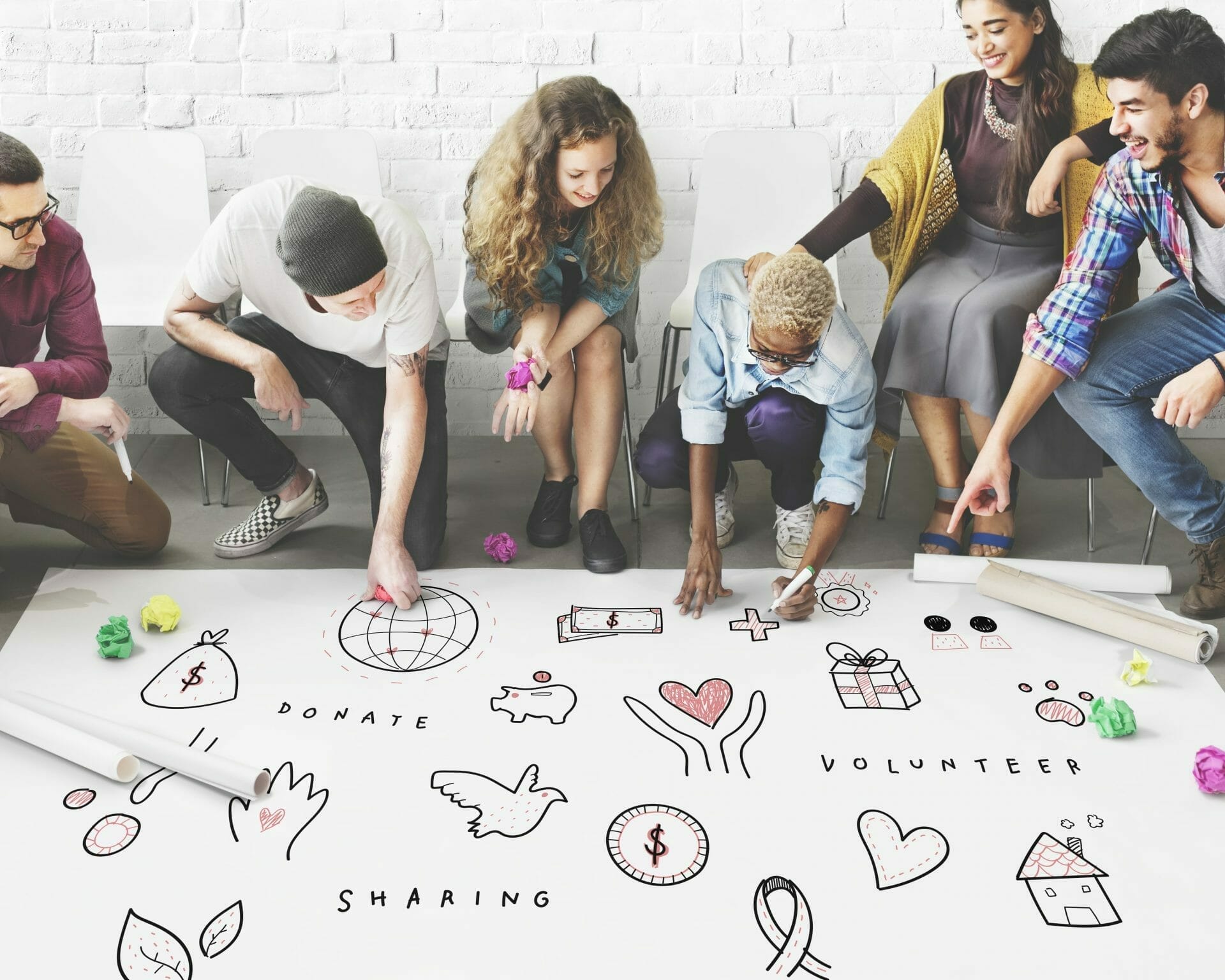 6 people creating large Charity visual with the words Donate, Volunteer, Sharing