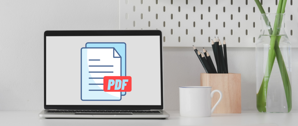 Laptop displaying PDF graphic next to a coffee cup and a pencil holder.