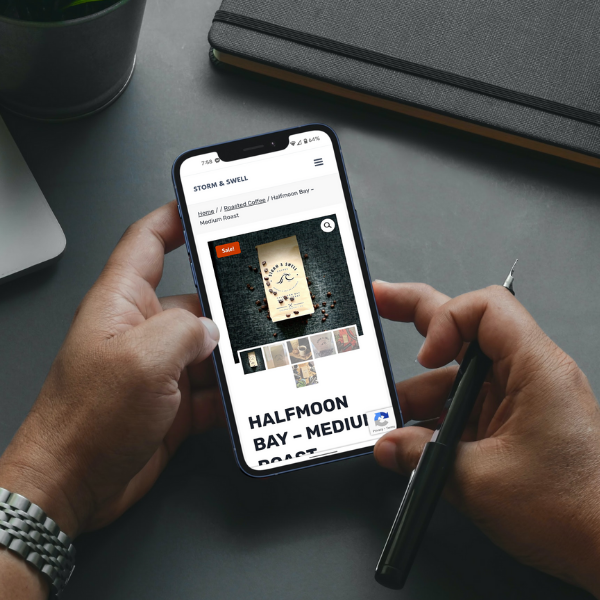 A person holding a cell phone displaying the Storm & Swell product design page.