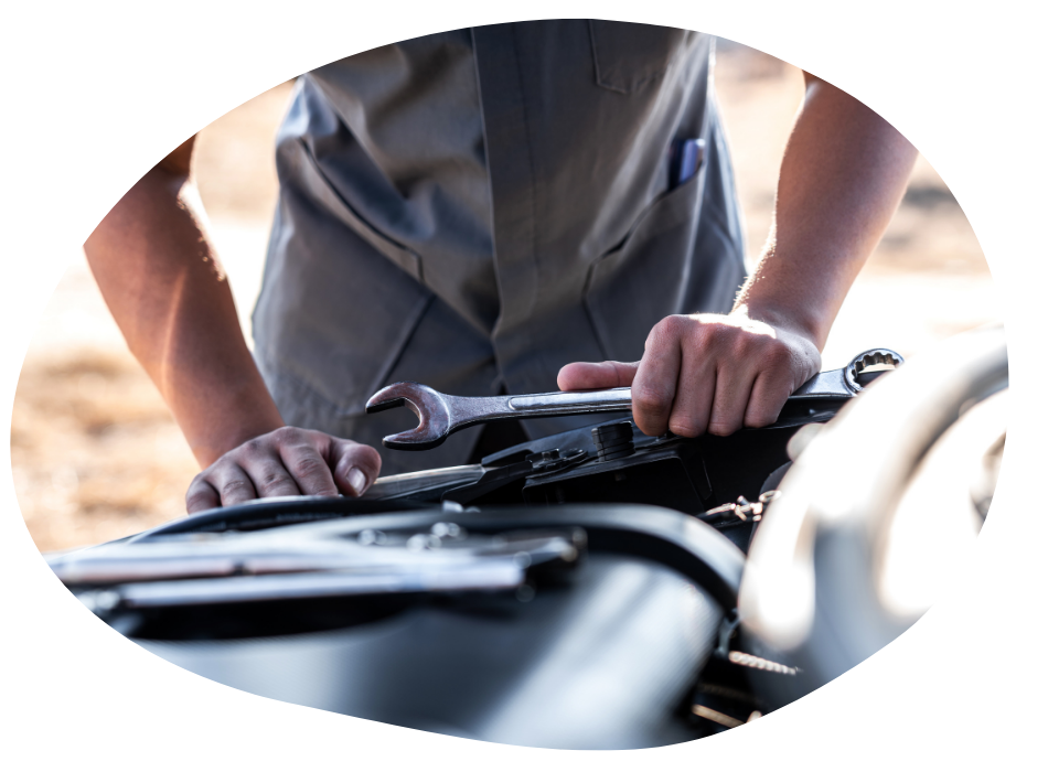 Person in a grey shirt holding a wrench while working on a vehicle engine.