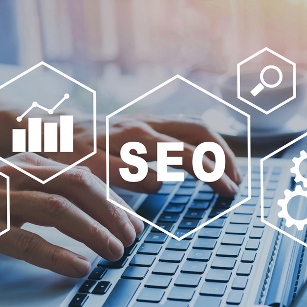 Hands typing on a laptop keyboard with transparent hexagons overlayed, displaying SEO-related icons and the word "SEO," symbolizing digital marketing and search engine optimization concepts.