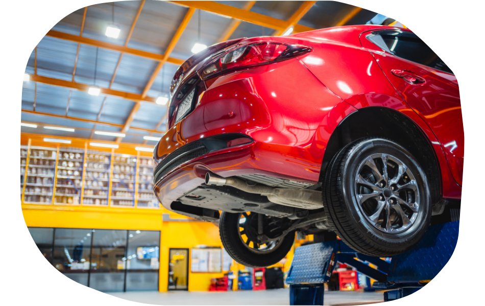 A red car is lifted on a hydraulic platform in a brightly lit auto repair shop with yellow walls, shelves of parts, and a modern look that could inspire industry specific web design.