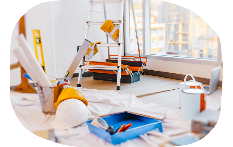 A room under renovation with a ladder, paint cans, a hard hat, tools, and industry specific web design plans scattered on a floor covered by a drop cloth near large windows.
