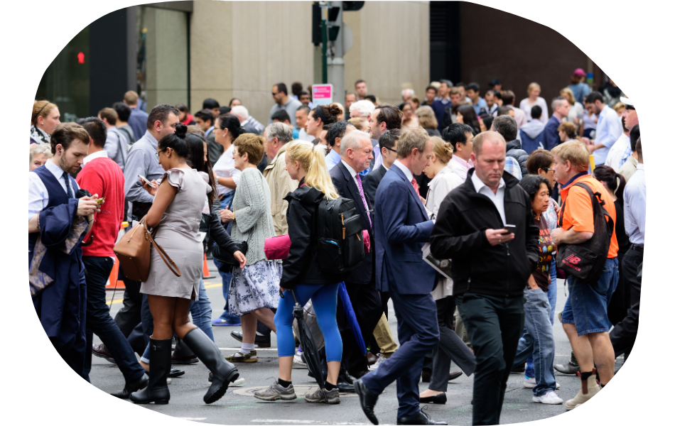 A large crowd of people walk in different directions at a busy city crosswalk, many looking at their phones or talking—reflecting the need for industry specific web design that caters to both business and casual users on the go.